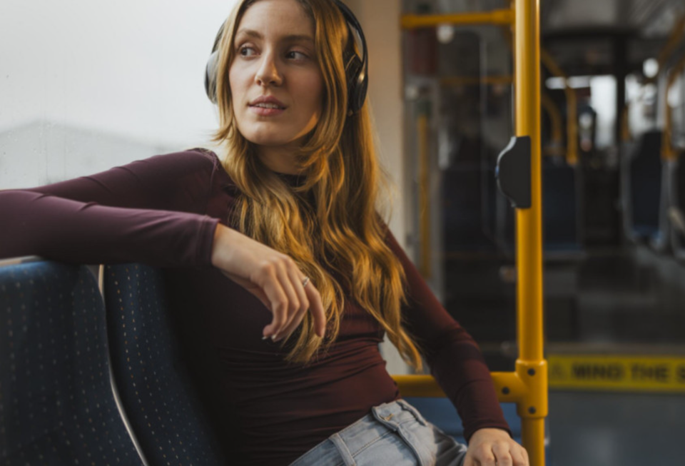 A passenger wearing headphones looks out of a tram window