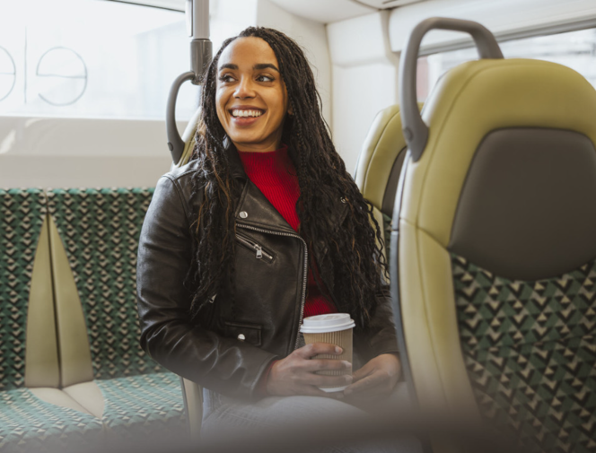 A smiling passenger with a coffee on a bus