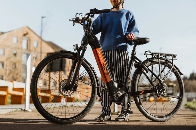 A cyclist standing beside an electric bike